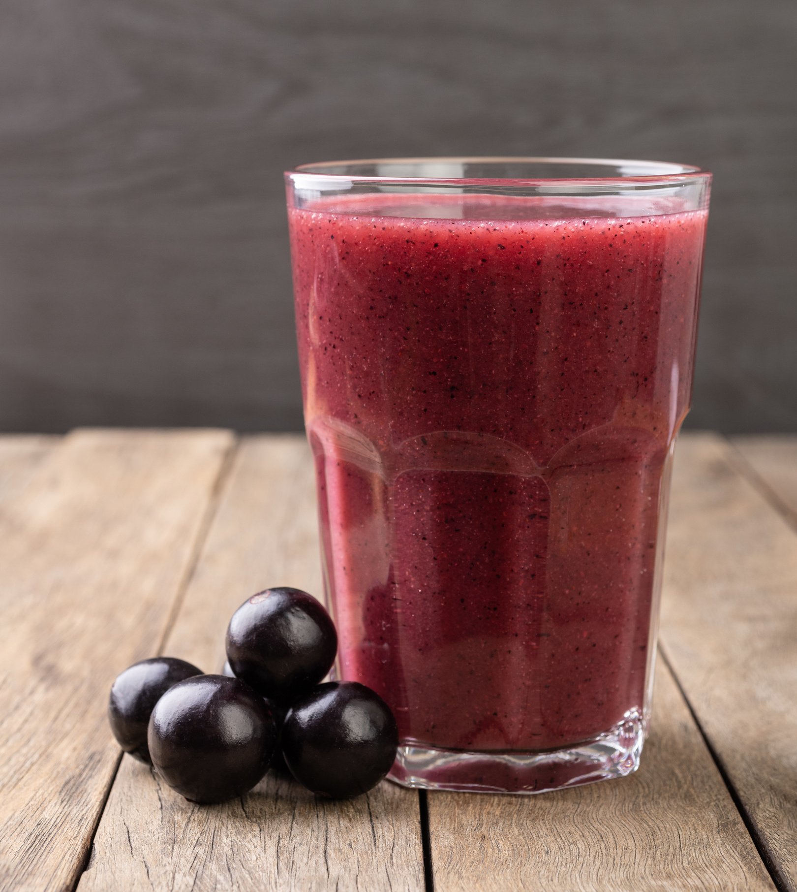 Jabuticaba juice with fruits over wooden table